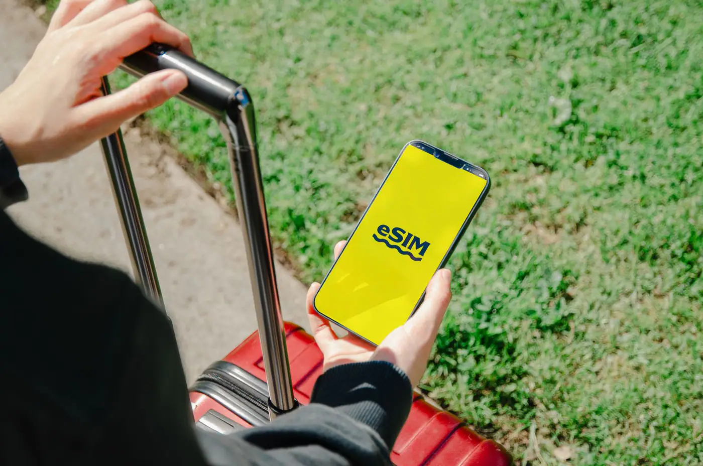 Viajante segurando um celular com eSIM ao lado de uma mala