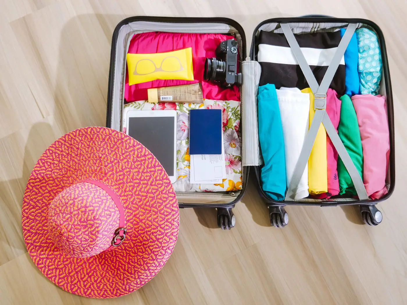 Mala aberta e organizada com roupas, câmera e itens essenciais para uma viagem