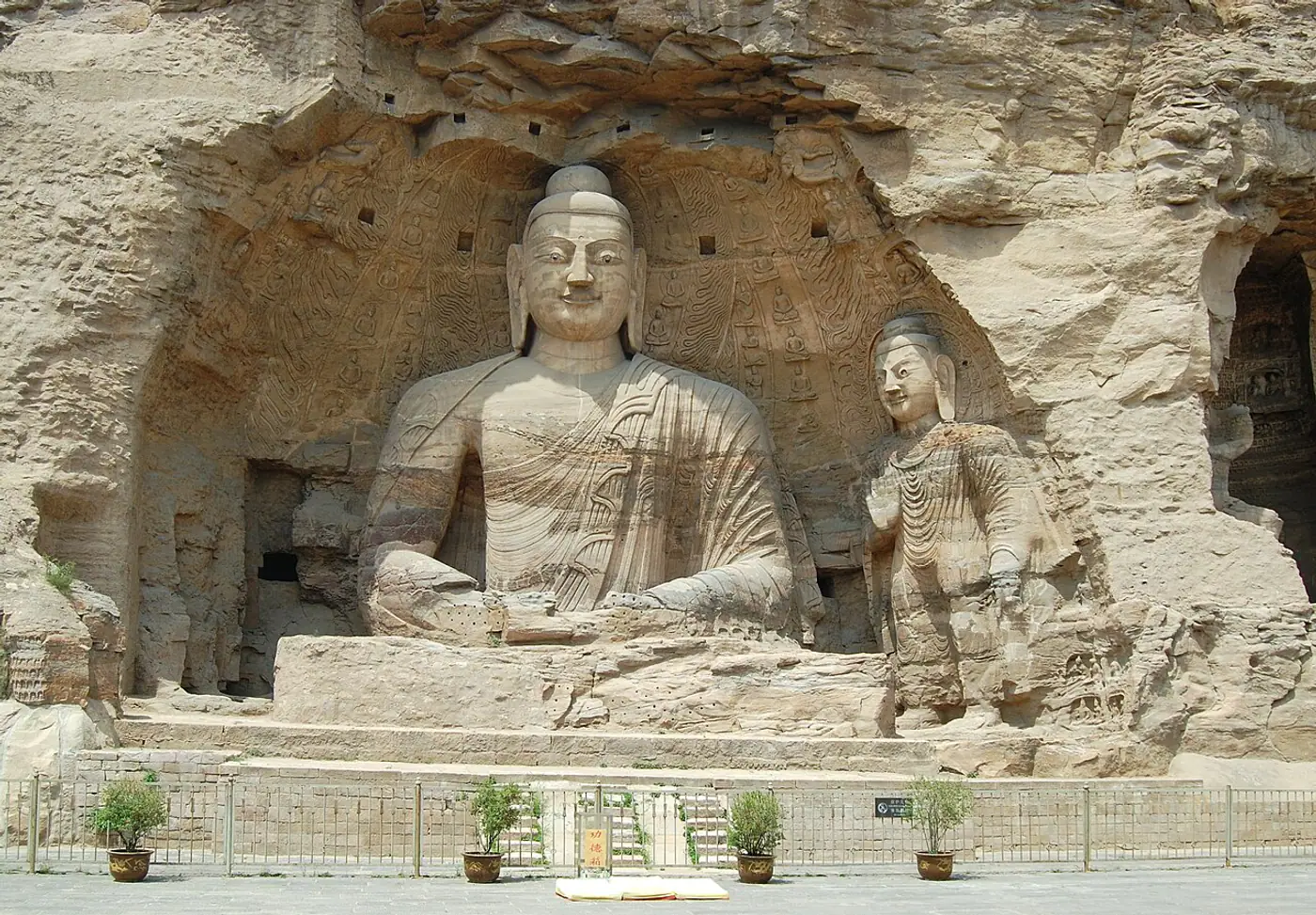 Grande Buda e escultura lateral talhados na rocha nas Grutas de Yungang