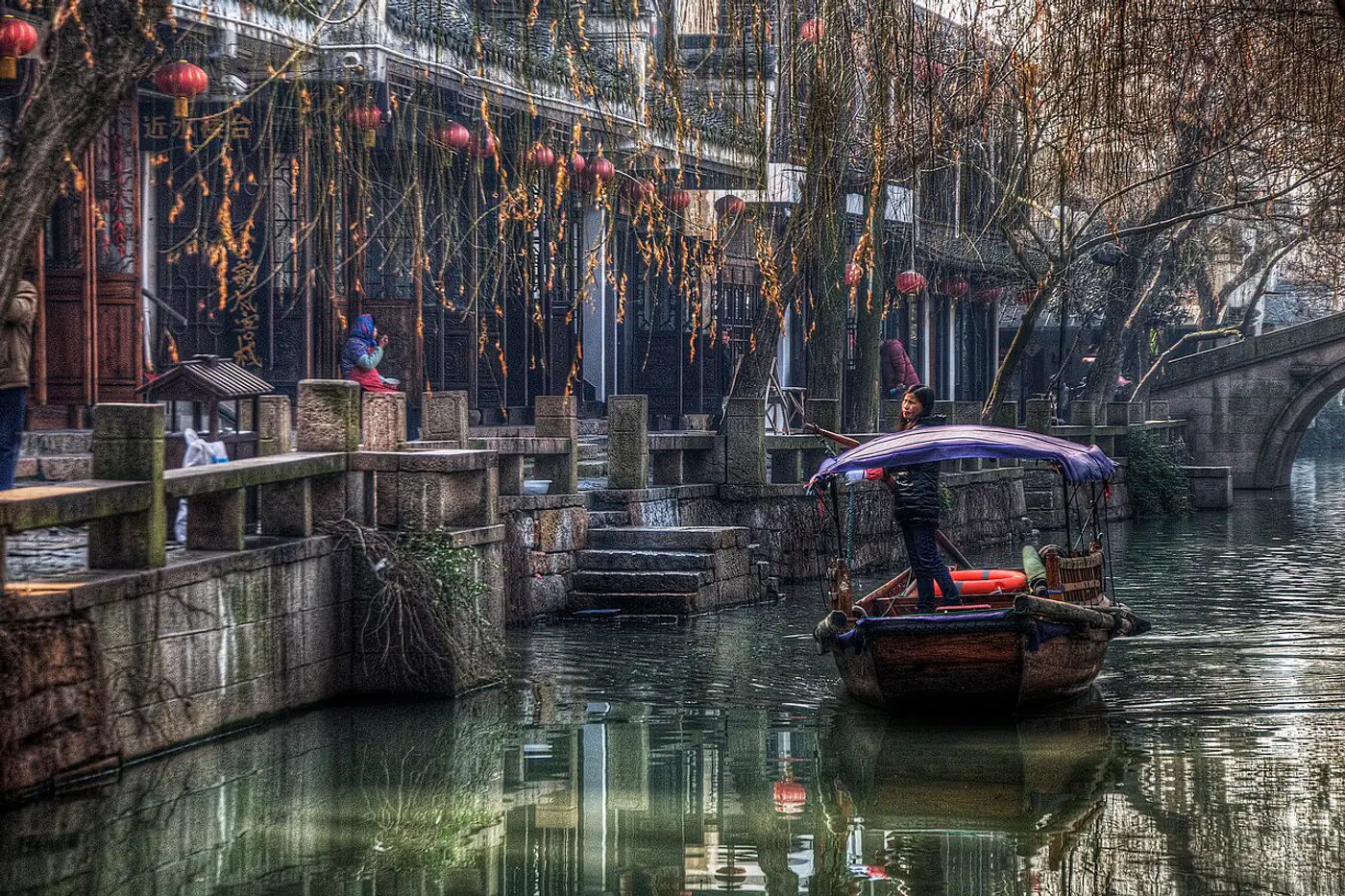 Barqueira conduzindo um barco tradicional por um canal de Zhouzhuang